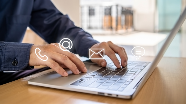 Person clicking on laptop with email and phone icons hovering around